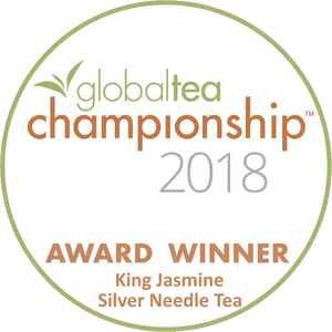 Circular white award badge with green and orange text, featuring the ’global tea championship 2018’’ logo and identifying king jasmine silver needle tea as an award winner.