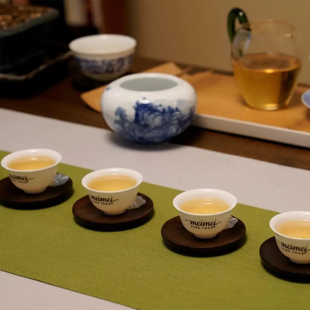 White ceramic tea cups with blue floral patterns, each resting on a dark wooden coaster.