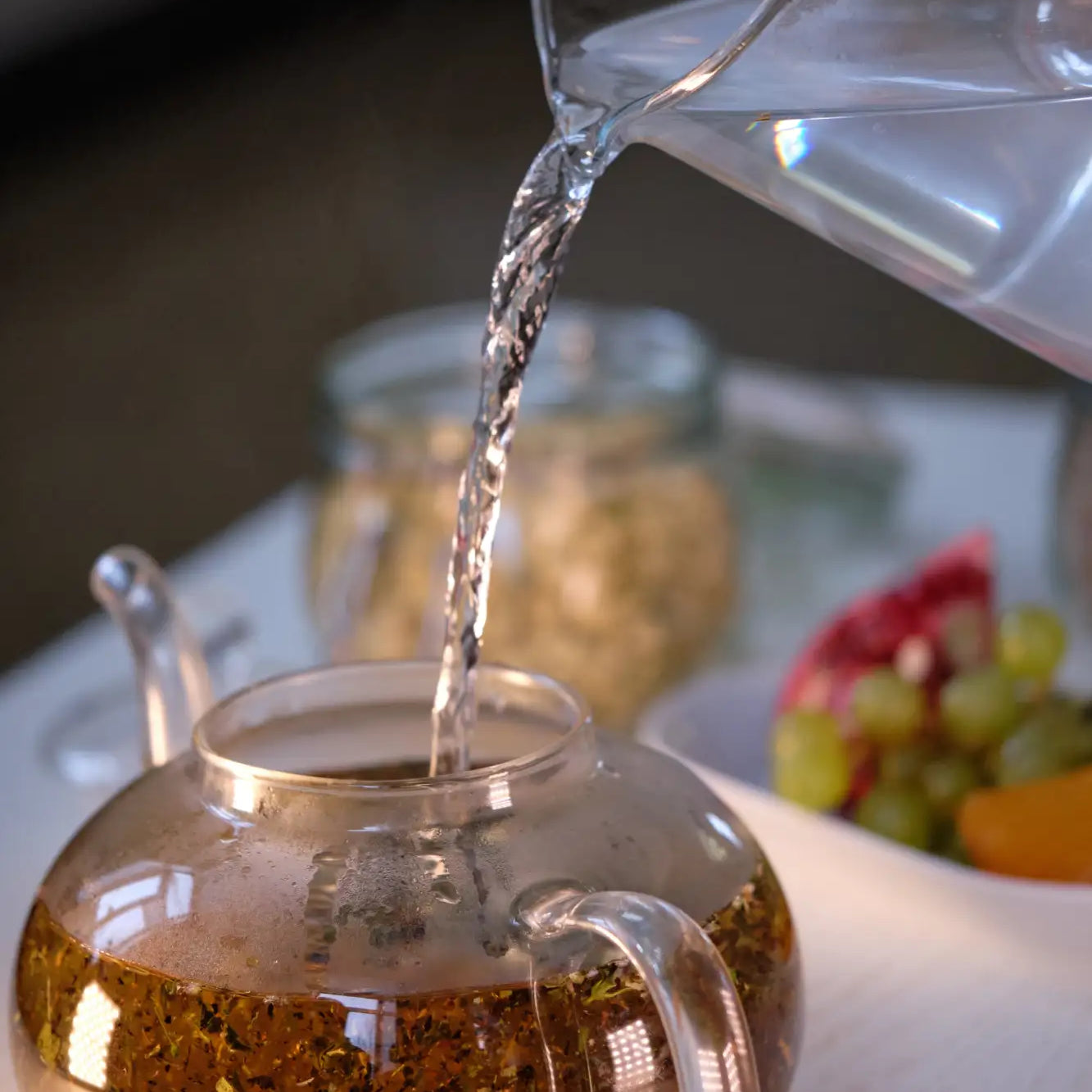 Clear glass teapot filled with golden-brown herbal tea leaves.