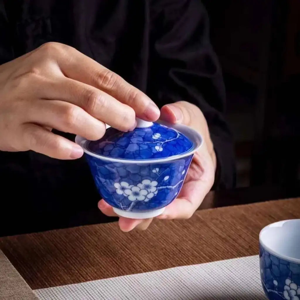 A blue and white porcelain covered tea bowl with delicate plum blossom patterns.